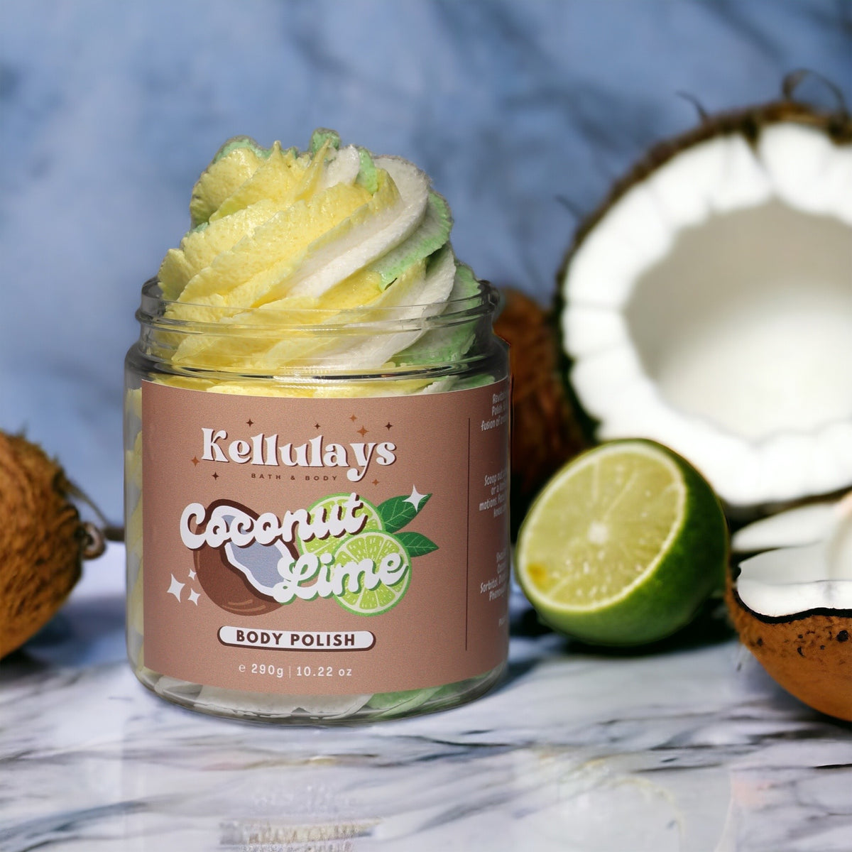 A jar of Kellulays Coconut Lime Body Polish with a swirl of yellow, white, and green, surrounded by halved coconuts and a lime, emphasizing its tropical fragrance.