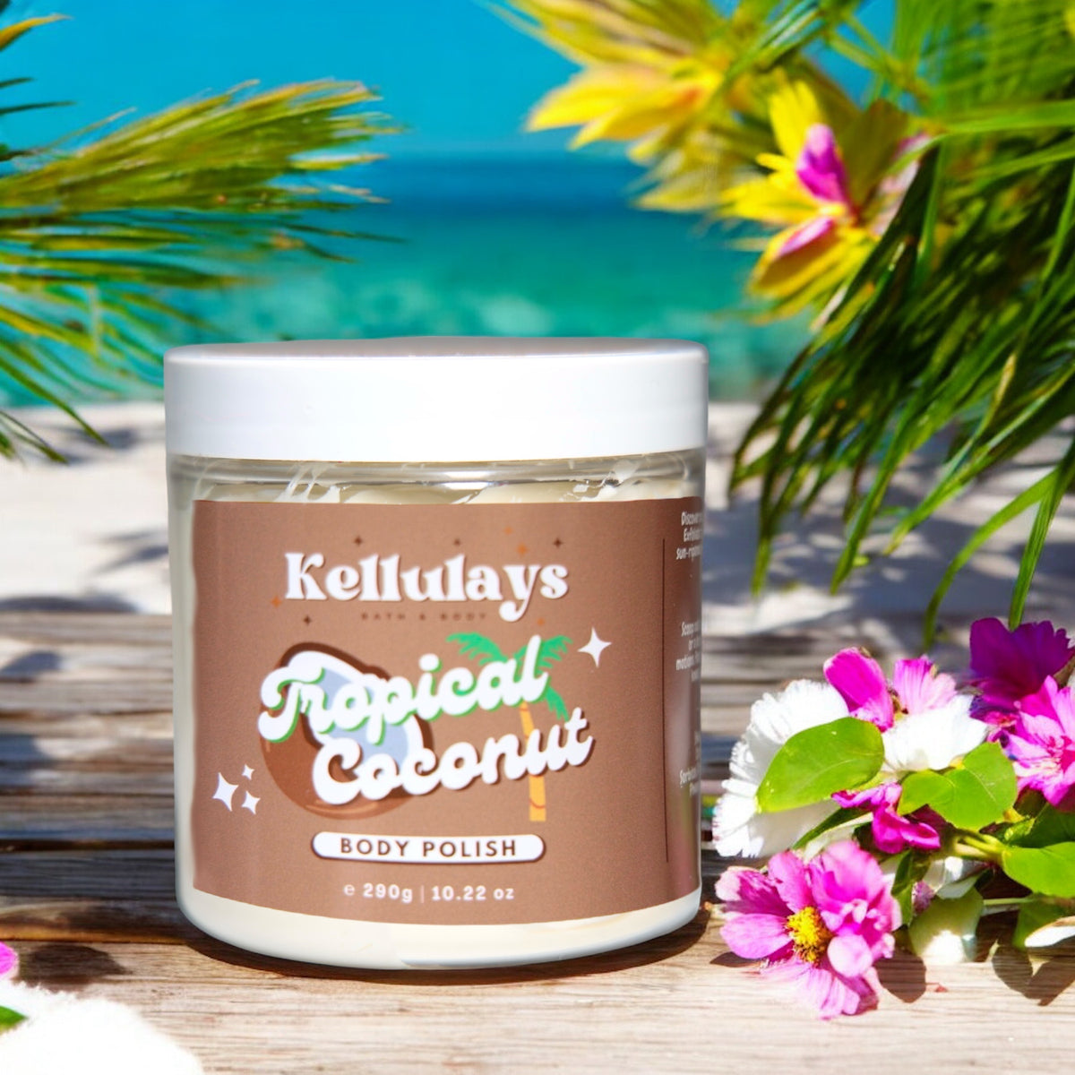 Jar of Kellulays Tropical Coconut Body Polish on a wooden deck, surrounded by colourful flowers and palm leaves, with a clear blue ocean and sky in the background, evoking a tropical paradise.