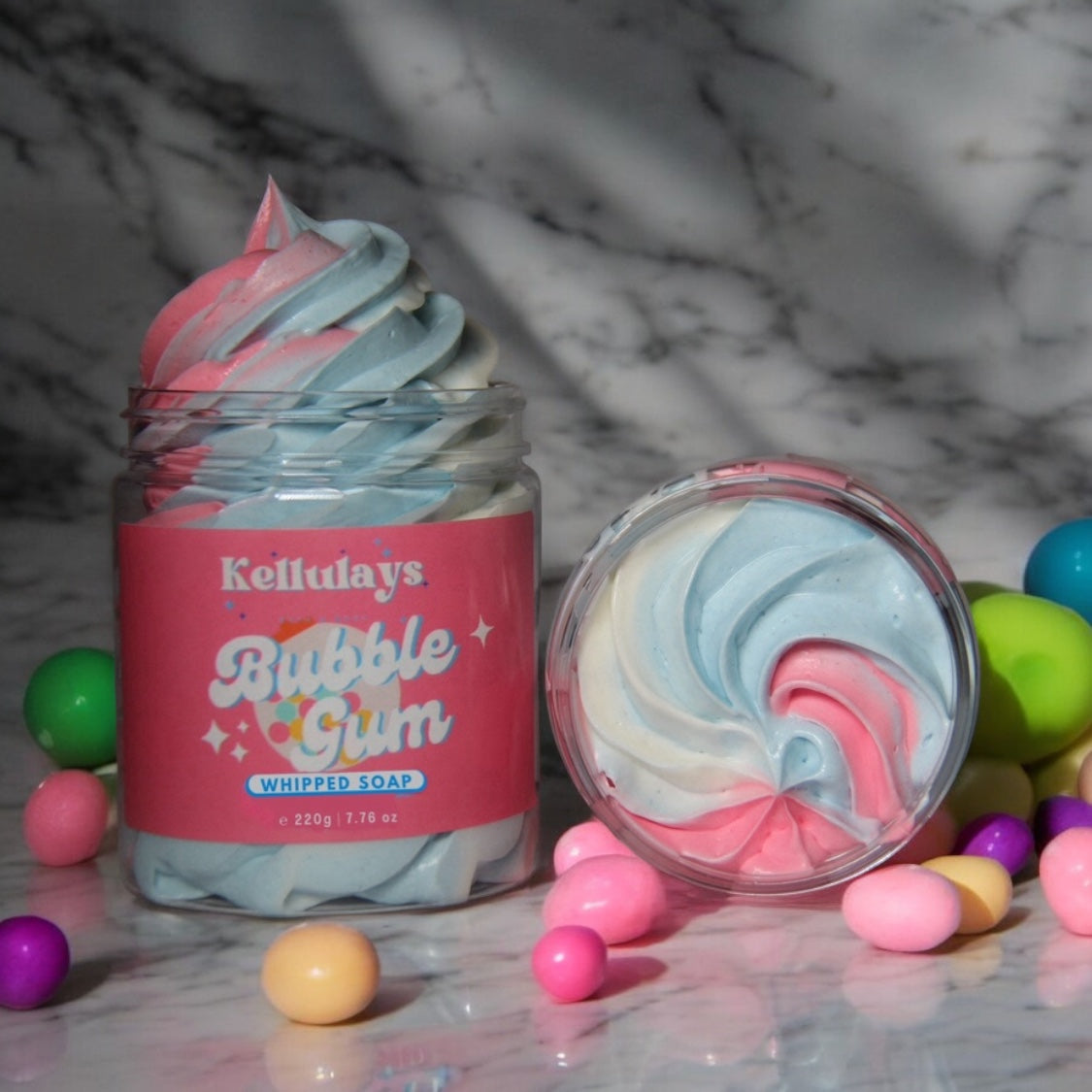 Handmade Kellulays Bubblegum Whipped Soap in a jar, featuring a colorful pink, white, and blue swirl design. This luxurious bath whip offers a playful and aromatic bubblegum scent, perfect for a fun and refreshing bath experience. The vibrant colors and creamy texture highlight the quality craftsmanship and unique artistry behind each handmade product.