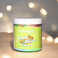 Jar of Kellulays ‘Cereal Killer’ body polish with a green label featuring a colorful cereal bowl image, set against a blurred background with glowing lights.